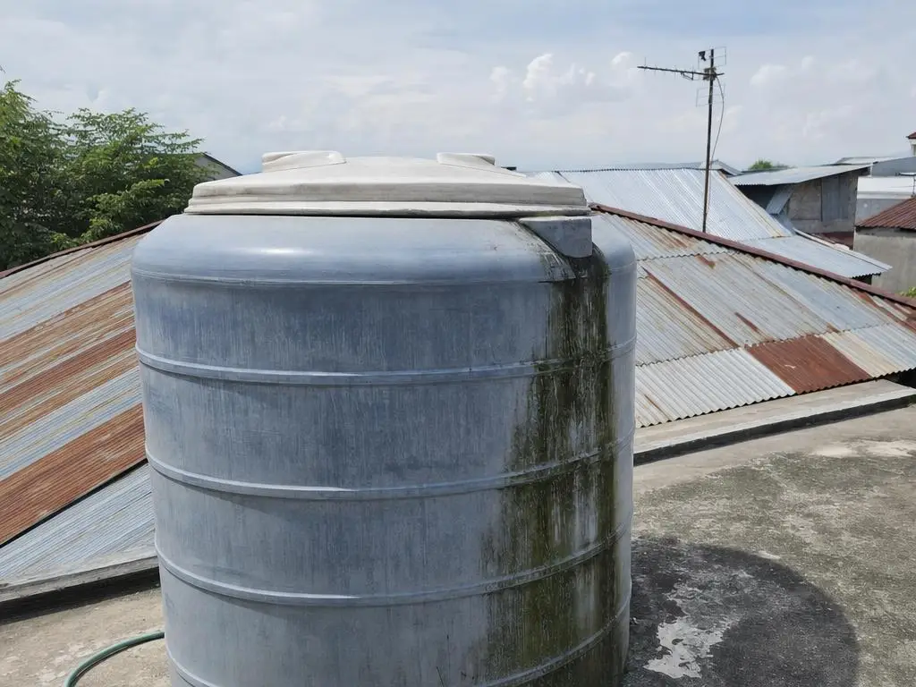 Tutup toren berdebu, atap seng dan antena terlihat di belakangnya