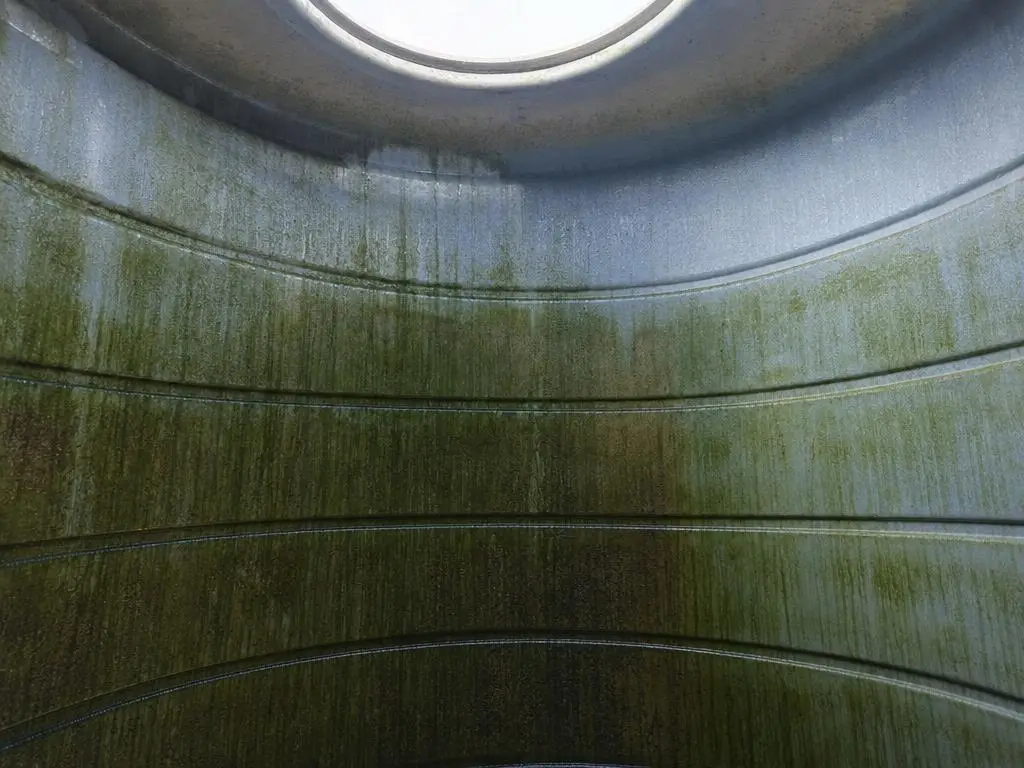 Dinding dalam toren berlapis lendir hijau dengan garis endapan mineral