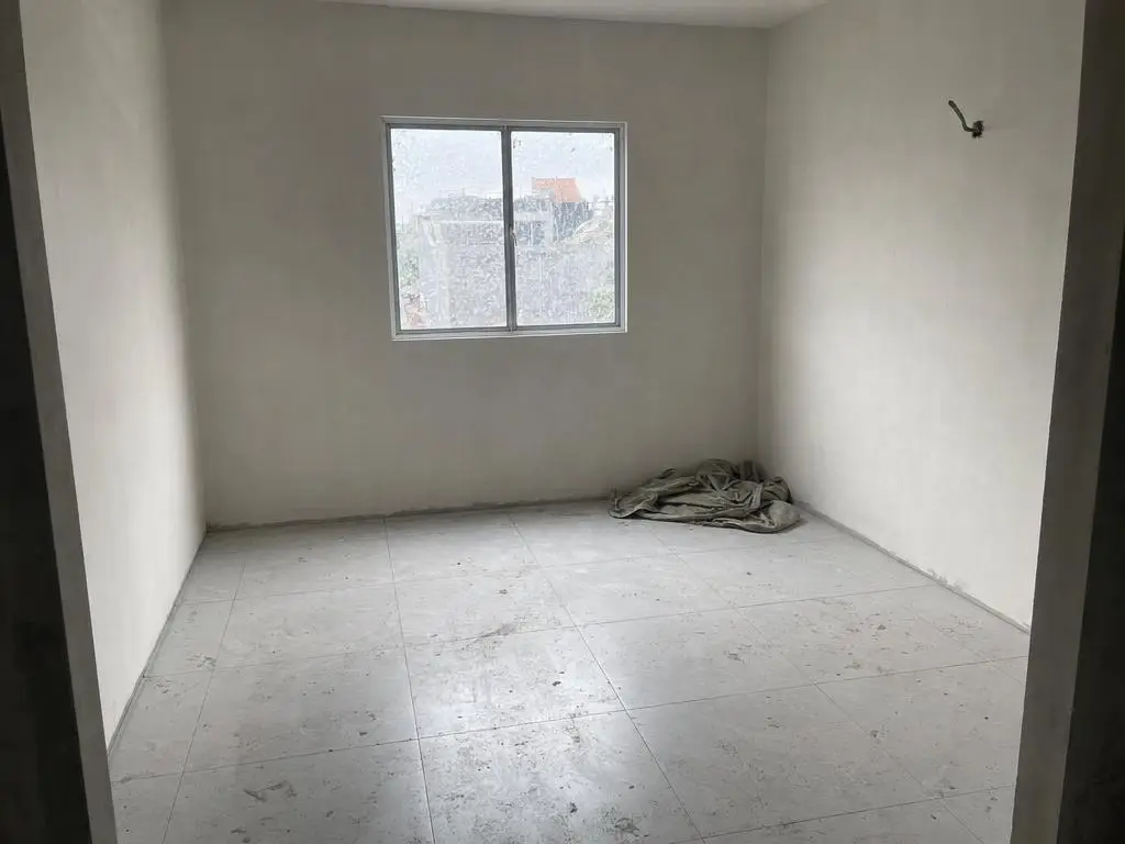 Ruangan kosong berdinding putih baru, lantai keramik abu abu tertutup debu semen dan bercak cat
